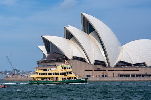 View of the Sydney Opera House with a ferry passing by in Sydney Harbour, Australia.